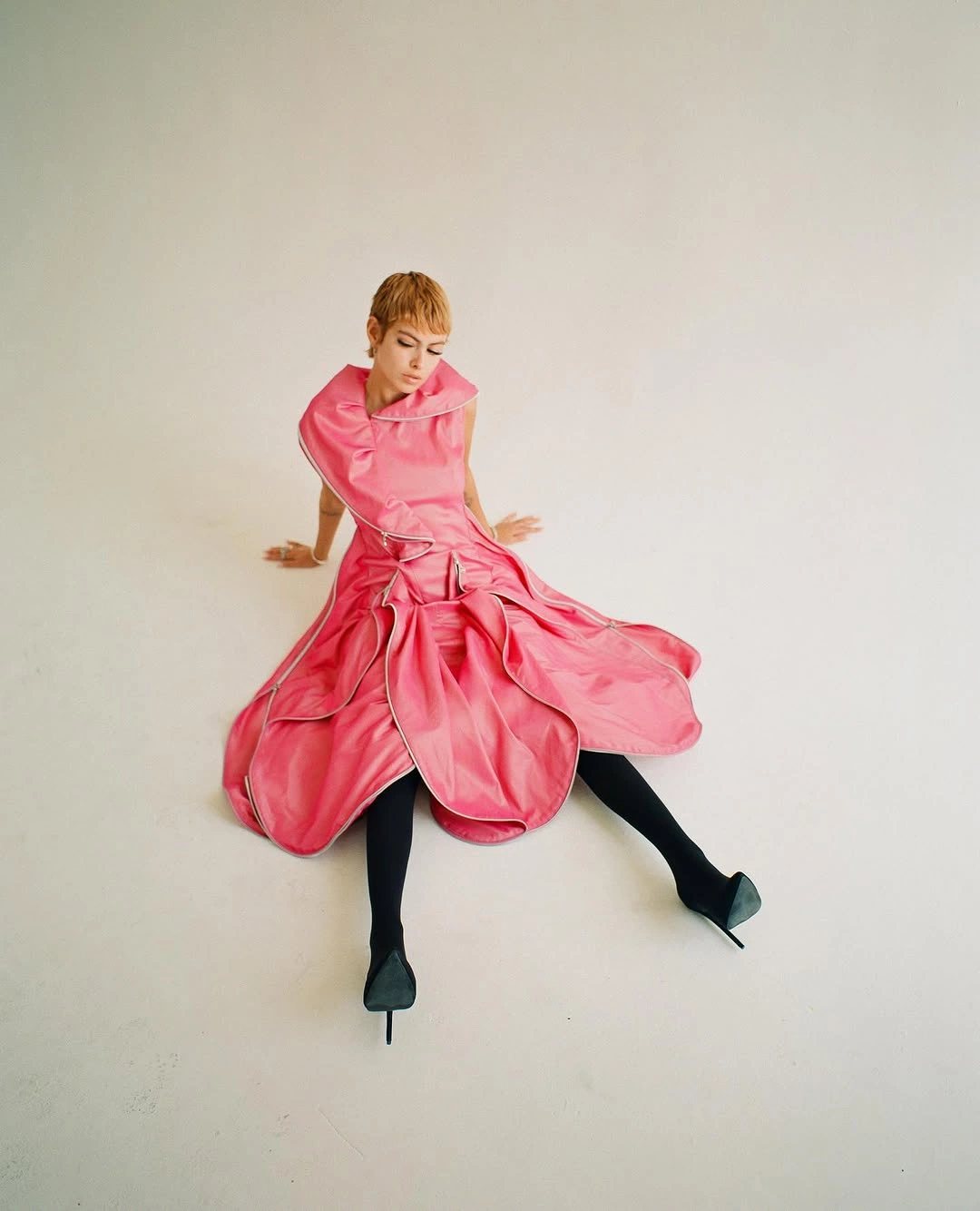 Pink zip dress, seated on floor, white cyclorama